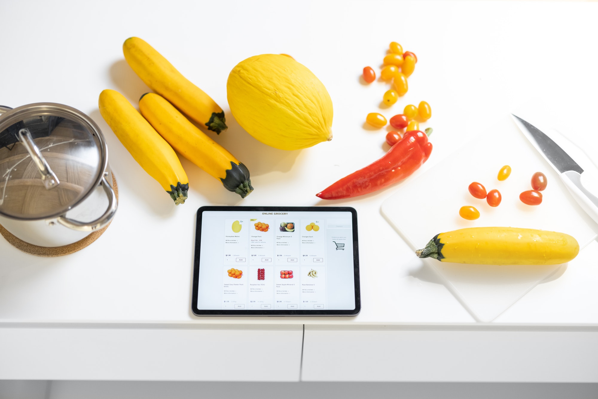 fresh vegetables and digital table with running e shop website on the white table